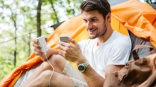 muž nabíjí telefon u stanu