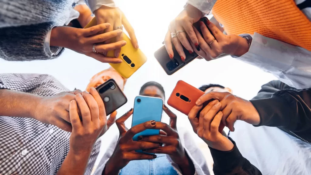 aplikace2 - Techsvět Skupina lidí stojících v kruhu, kteří drží různé barevné smartphony.