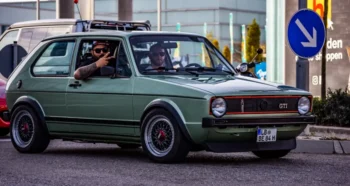 Volkswagen Golf GTI Mk1 ve skvělém stavu. Auto má typickou karoserii první generace s červeným rámečkem v masce chladiče, černými plastovými nárazníky a sportovními koly BBS.