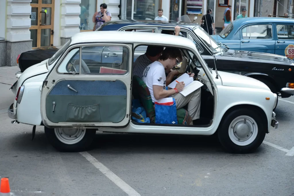 auto1 - Techsvět Bílé auto ZAZ-965, zaparkované ve městě s otevřenými dveřmi.