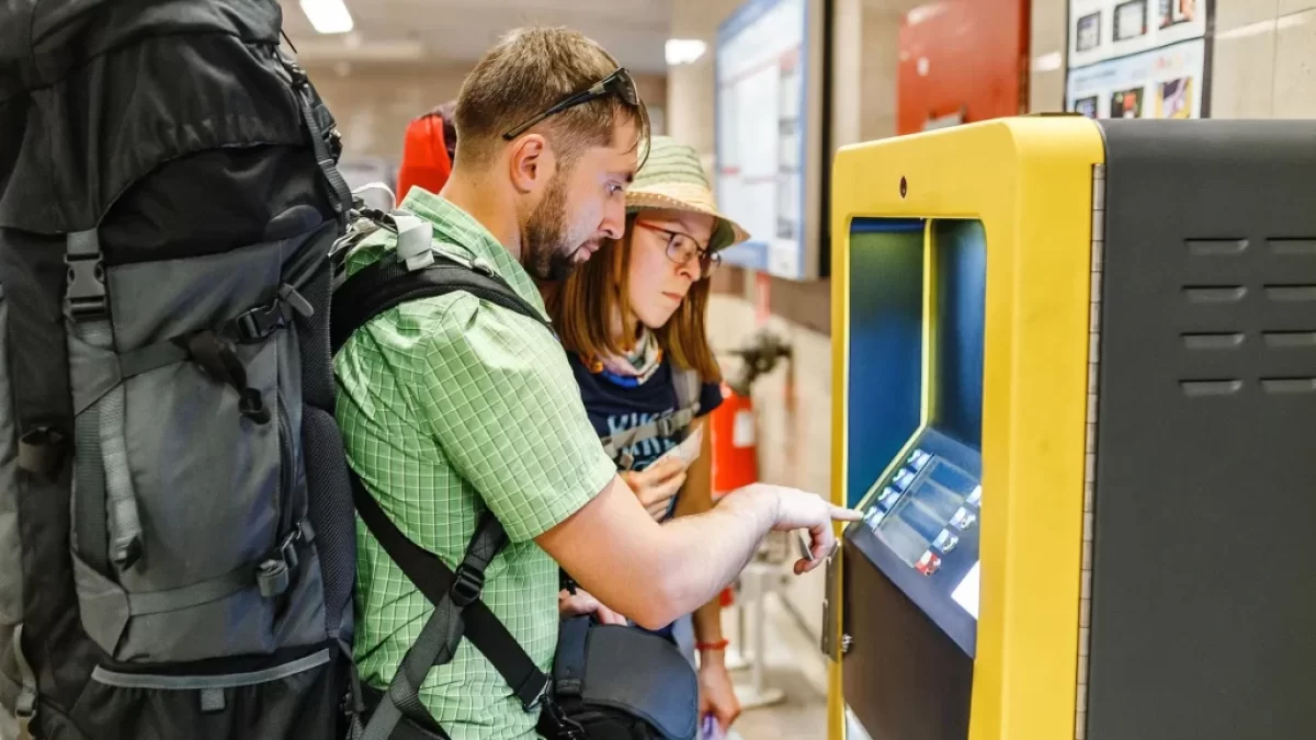 Mladý pár s batohy vybírá z bankomatu