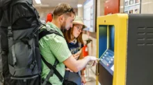 Mladý pár s batohy vybírá z bankomatu