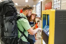 Mladý pár s batohy vybírá z bankomatu