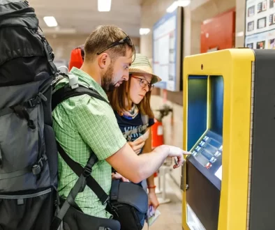 Mladý pár s batohy vybírá z bankomatu
