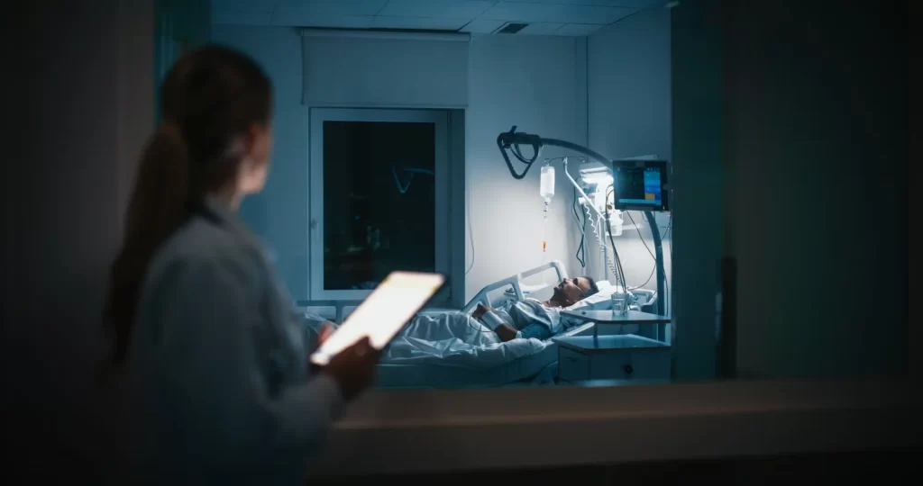 doktor2 - Techsvět Zdravotní sestra sleduje pacienta ležícího na lůžku na jednotce intenzivní péče.