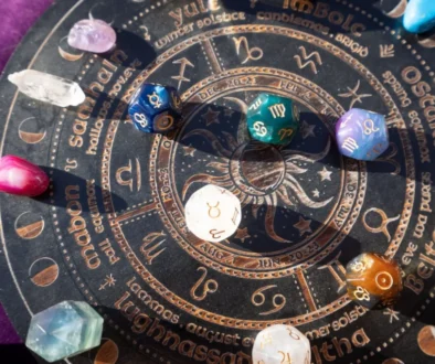Detailní záběr na astrologický kruh se symboly zvěrokruhu a osmihranné kostky s astrologickými a planetárními znaky.