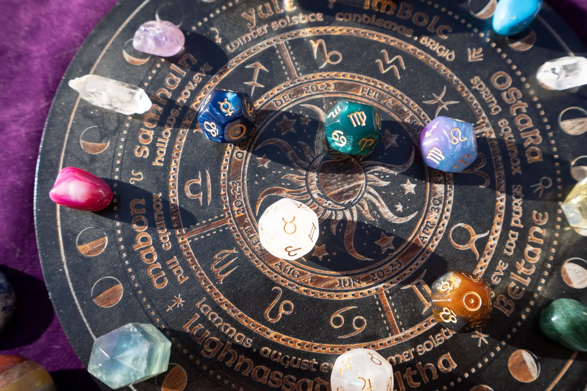 Detailní záběr na astrologický kruh se symboly zvěrokruhu a osmihranné kostky s astrologickými a planetárními znaky.