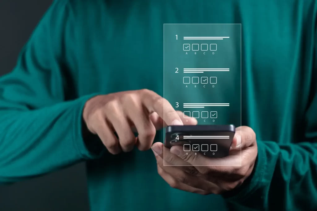 kviz2 - Techsvět Osoba v zelené mikině, která drží mobilní telefon a interaguje s dotykovým displejem.