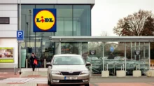 Vstup do prodejny Lidl s výrazným logem na moderní prosklené budově.