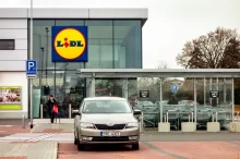 Vstup do prodejny Lidl s výrazným logem na moderní prosklené budově.