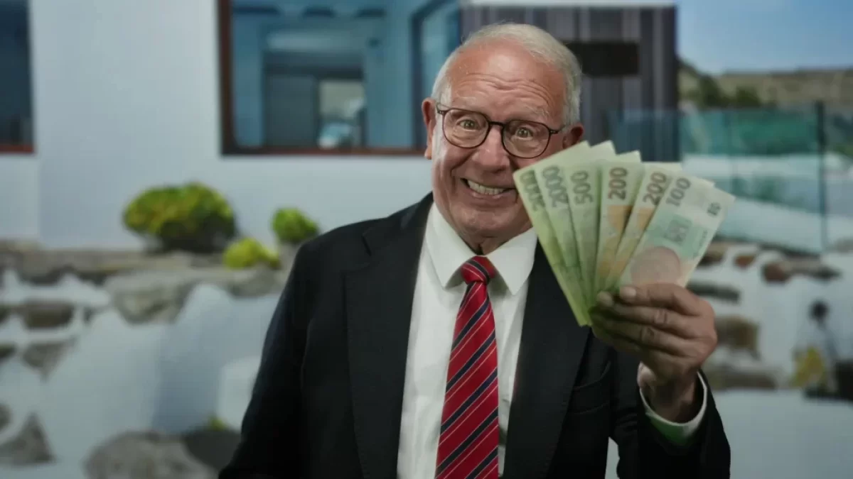 Senior v obleku ukazuje vějíř bankovek