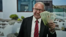 Senior v obleku ukazuje vějíř bankovek
