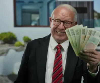 Senior v obleku ukazuje vějíř bankovek