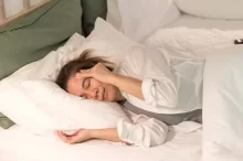 žena leží v posteli s bolestí hlavy