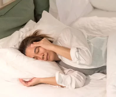 žena leží v posteli s bolestí hlavy