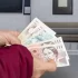 žena u bankomatu přepočítává peníze