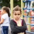 Malá holčička se zkříženýma rukama a vážným až naštvaným výrazem ve tváři. Stojí na dětském hřišti, kde si v pozadí hrají další děti.