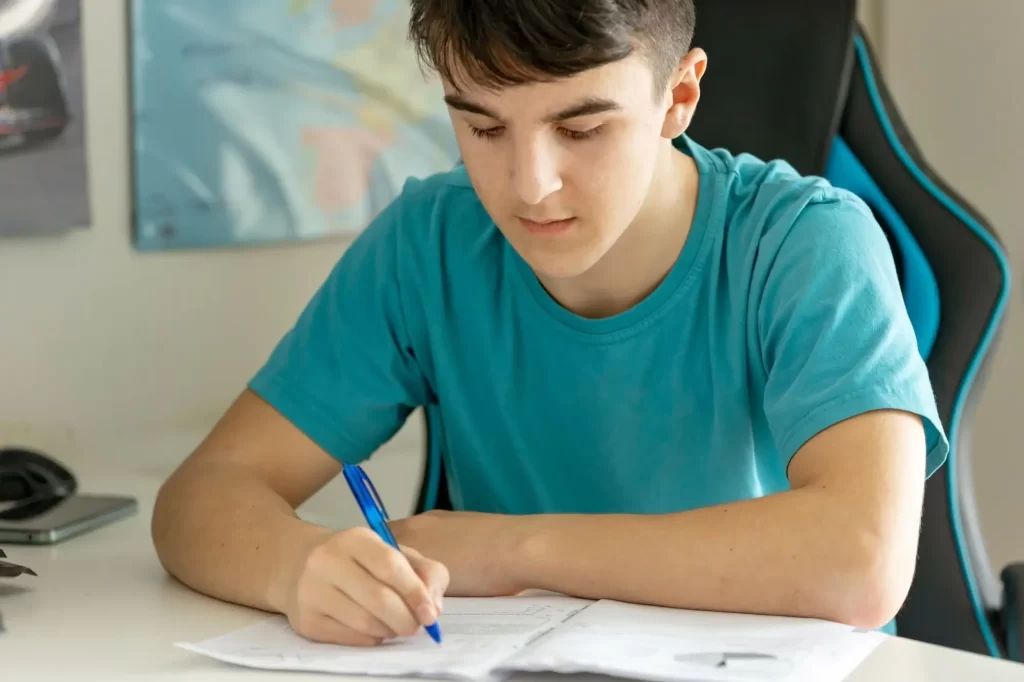 Mladý student sedící doma u psacího stolu.