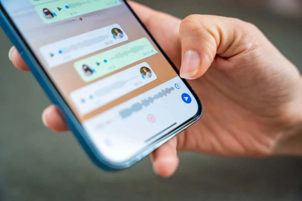 Ruka drží mobilní telefon se spuštěnou aplikací WhatsApp.