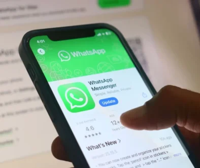 Detailní pohled na mobilní telefon, na kterém je otevřená stránka aplikace WhatsApp.