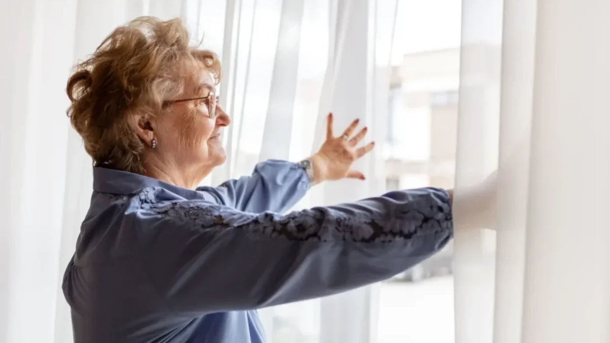 seniorka roztahuje záclony