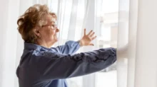 seniorka roztahuje záclony