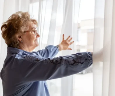 seniorka roztahuje záclony