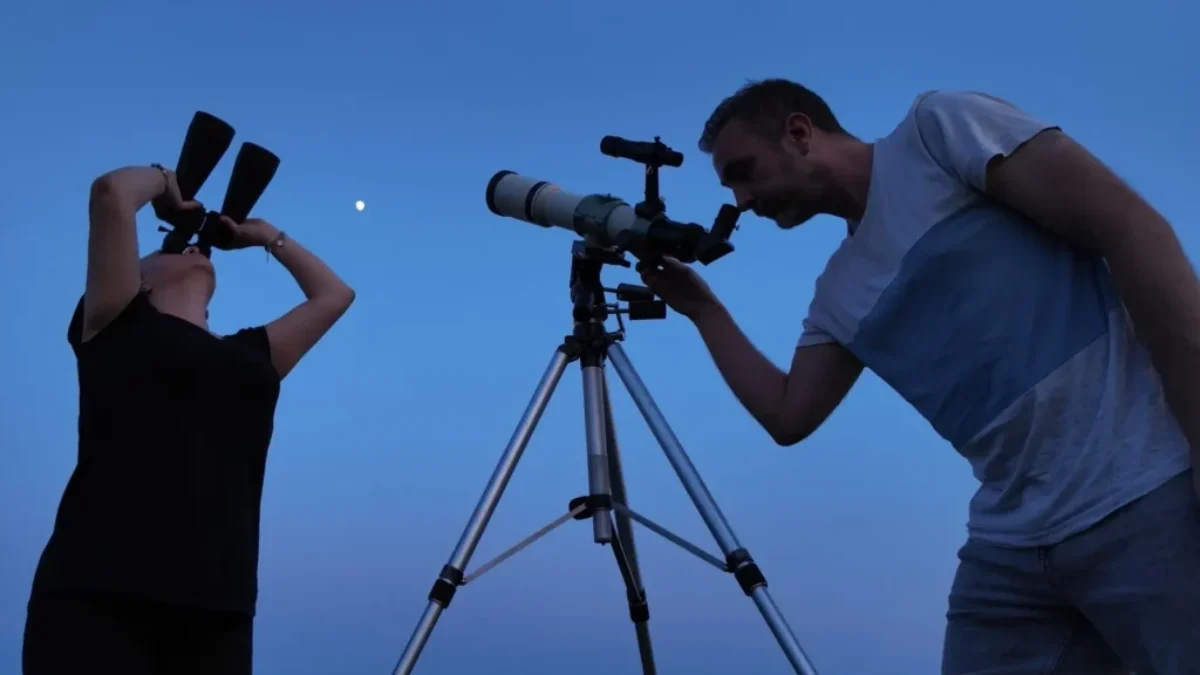 Muž a žene pozorují dalekohledem oblohu