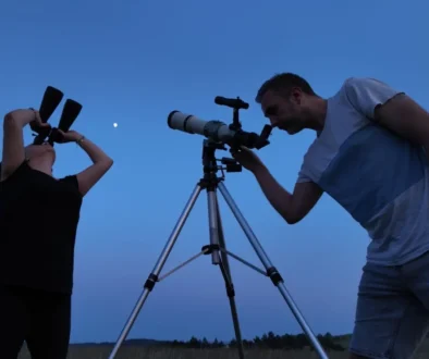Muž a žene pozorují dalekohledem oblohu