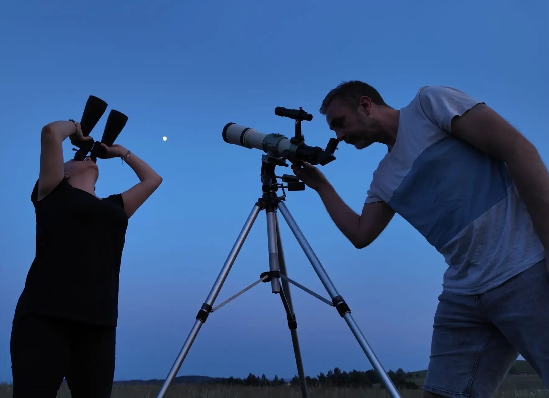 Muž a žene pozorují dalekohledem oblohu