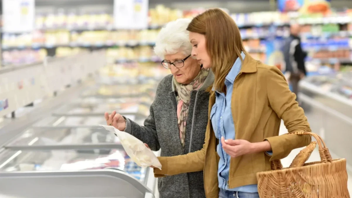 žena pomáhá s nákupem seniorce