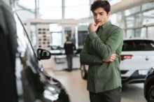 Muž v autosalonu přemýšlí nad výběrem auta
