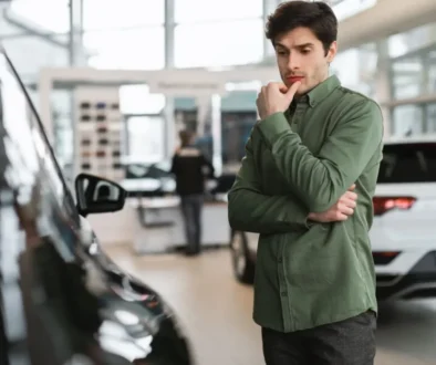 Muž v autosalonu přemýšlí nad výběrem auta