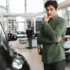 Muž v autosalonu přemýšlí nad výběrem auta
