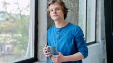 mladý kluk u okna s hrnkem kávy