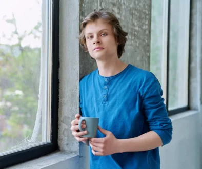 mladý kluk u okna s hrnkem kávy