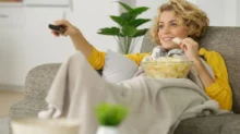 Žena sleduje televizi a jí chipsy