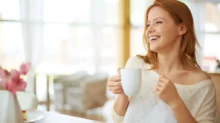 Usměvavá žena si vychutnává šálek horkého čaje.
