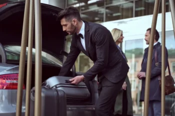 portýr vyndávající zavazadla z auta