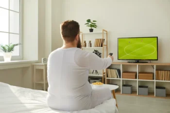 muž kouká doma na fotbal