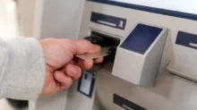 muž strká kartu do bankomatu