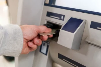 muž strká kartu do bankomatu