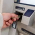 muž strká kartu do bankomatu
