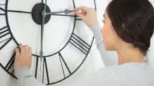 žena mění čas na svých hodinách v bytě