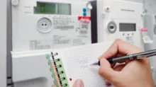 Osoba si zapisuje stav vysokého a nízkého tarifu na svém elektroměru
