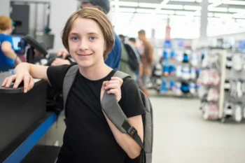 Chlapec stojí vedle pásu u pokladny, čeká až pokladní namarkuje zboží