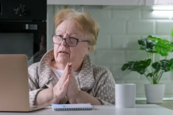 Starší žena v brýlích sedí u počítače