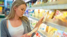 žena si důkladně čte složení sýra, který si chce koupit
