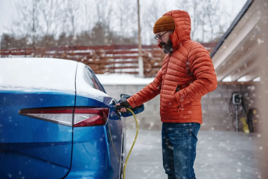 Muž nabíjí v zimě elektromobil