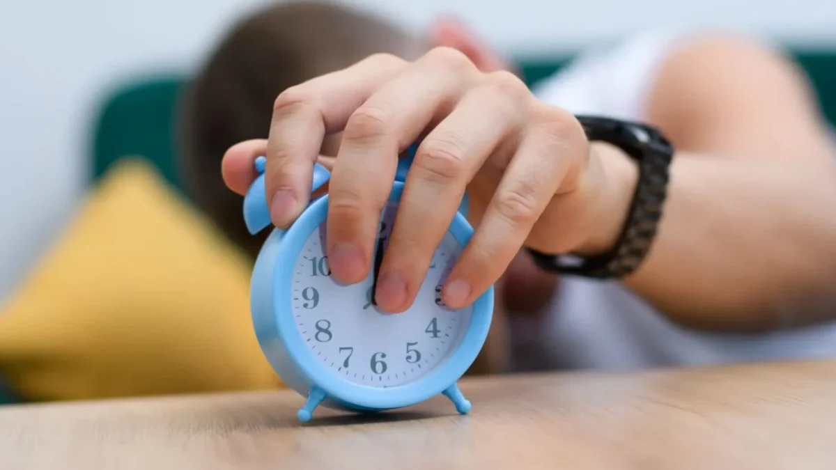 detail na mužskou ruku sahající na budík